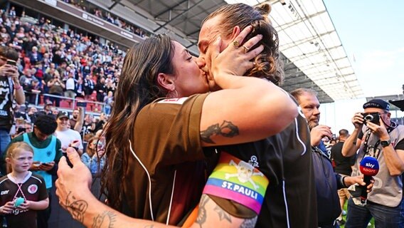 St. Paulis Jackson Irvine und seine Freundin Jemilla Pir geben sich nach dem geschafften Bundesliga-Aufstieg einen Kuss. © Witters/ValeriaWitters 